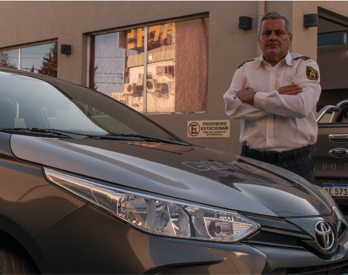 Empleado de seguridad de Giomon con los brzos cruzados al lado de un auto